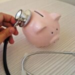 Stethoscope resting on a pink piggy bank, representing the cost of health insurance