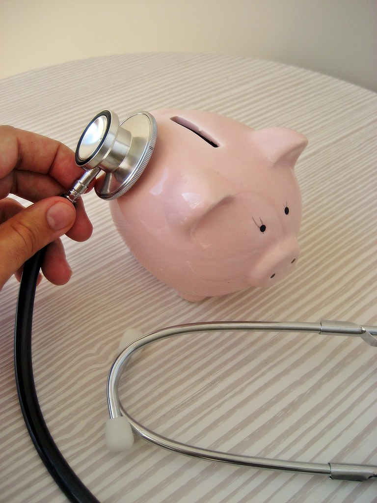 Stethoscope resting on a pink piggy bank, representing the cost of health insurance