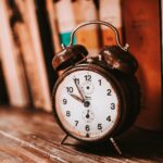 Vintage alarm clock on a wooden bookshelf, a reminder to set clocks back when daylight saving time ends