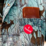 Red "I Voted" sticker on the pocket of a patterned blue shirt