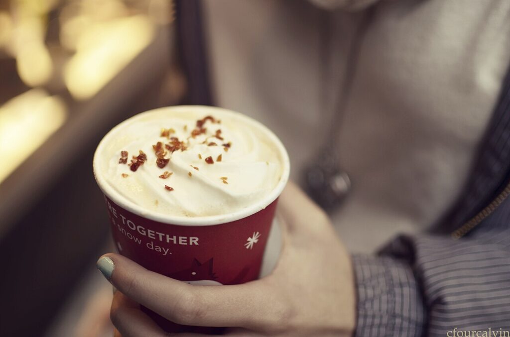 Starbucks Caramel Brulee Latte topped with whipped cream in a red holiday cup