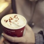 Starbucks Caramel Brulee Latte topped with whipped cream in a red holiday cup